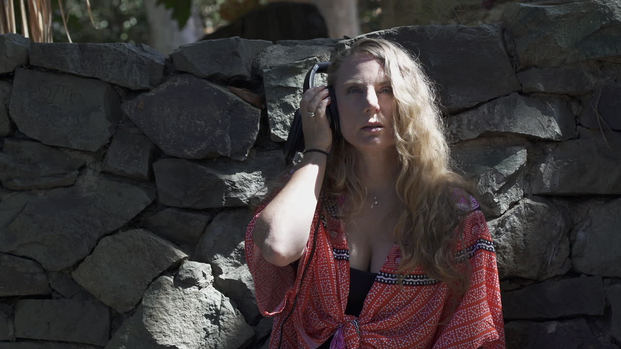 Stylish blonde woman grooving out to music in headphones outdoors