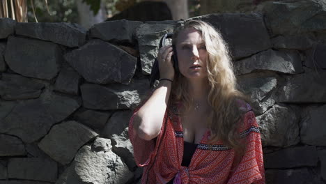 stylish blonde woman grooving out to music in headphones outdoors