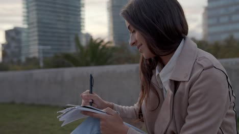 A-Young-Beautiful-Woman-Entrepreneur-handwriting-after-work-and-taking-notes-Close-Up-medium-shot-on-a-city