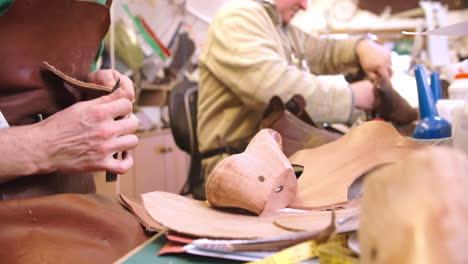 bespoke shoemaker measuring and cutting leather for shoe