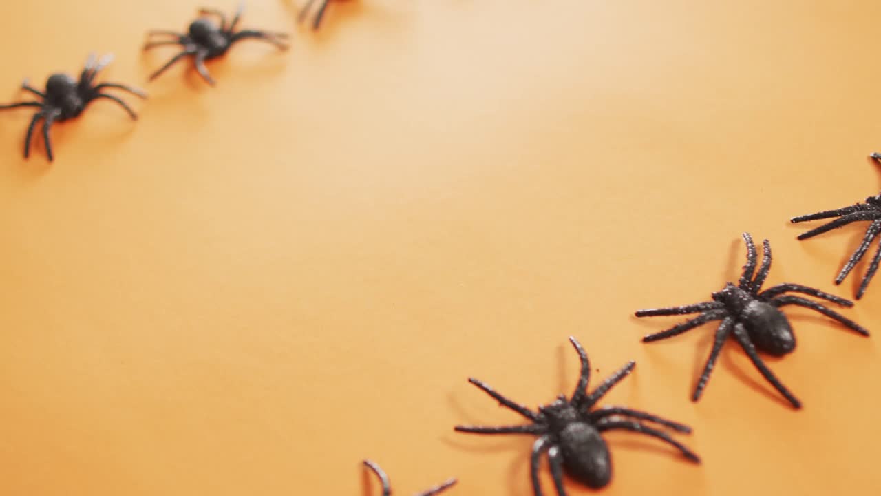 Närbild av flera spindelleksaker med kopieringsutrymme mot orange bakgrund