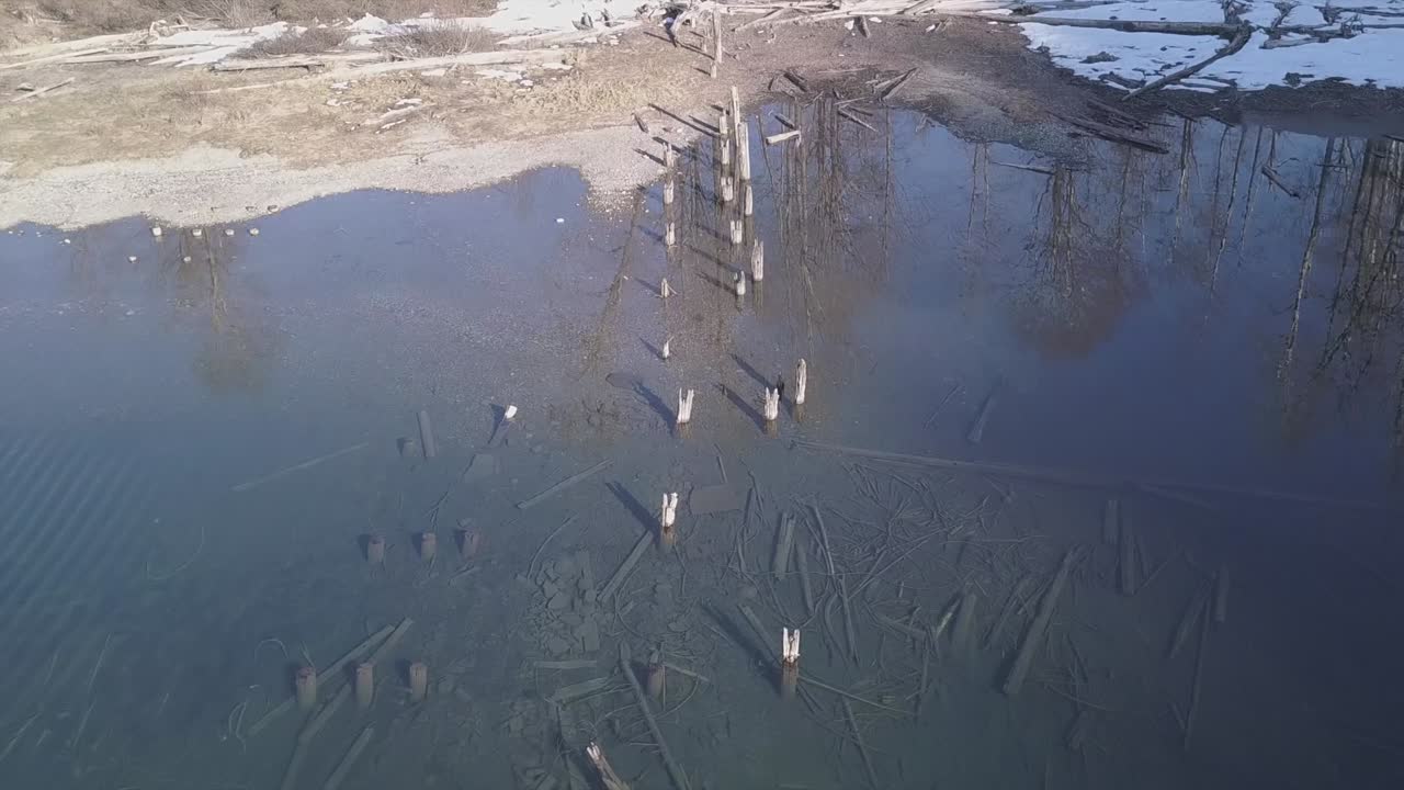 Historic piling remains of old pier in clear water of mountain lake