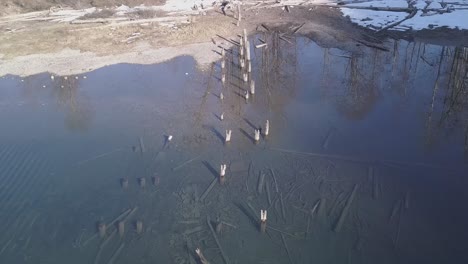 historic piling remains of old pier in clear water of mountain lake