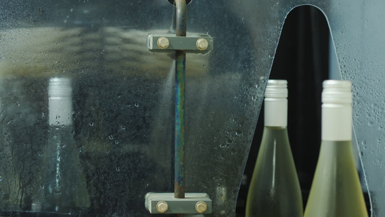 컨베이어를 따라 물로 세척되는 차로 이동하는 와인 병