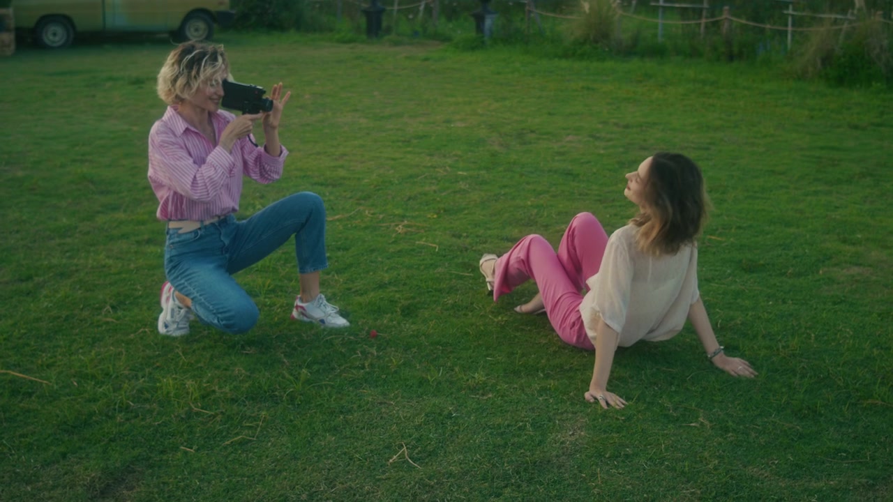 Young Woman Filming Her Friend Sitting on Grass in a Garden