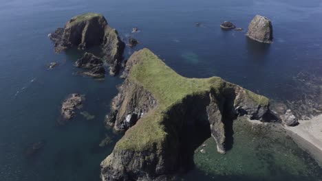 Die-Luftaufnahme-Zeigt-Erodierte-Meereshöhlen-Auf-Einer-Zerklüfteten-Insel-Im-Blauen-Meer