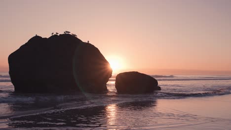 otherwordly lens flare from behind rock boulders during low tide at beach