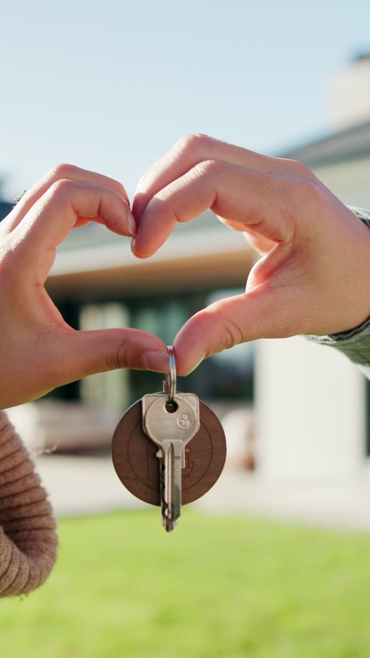 Coppia che tiene le chiavi di casa formando un cuore con le mani