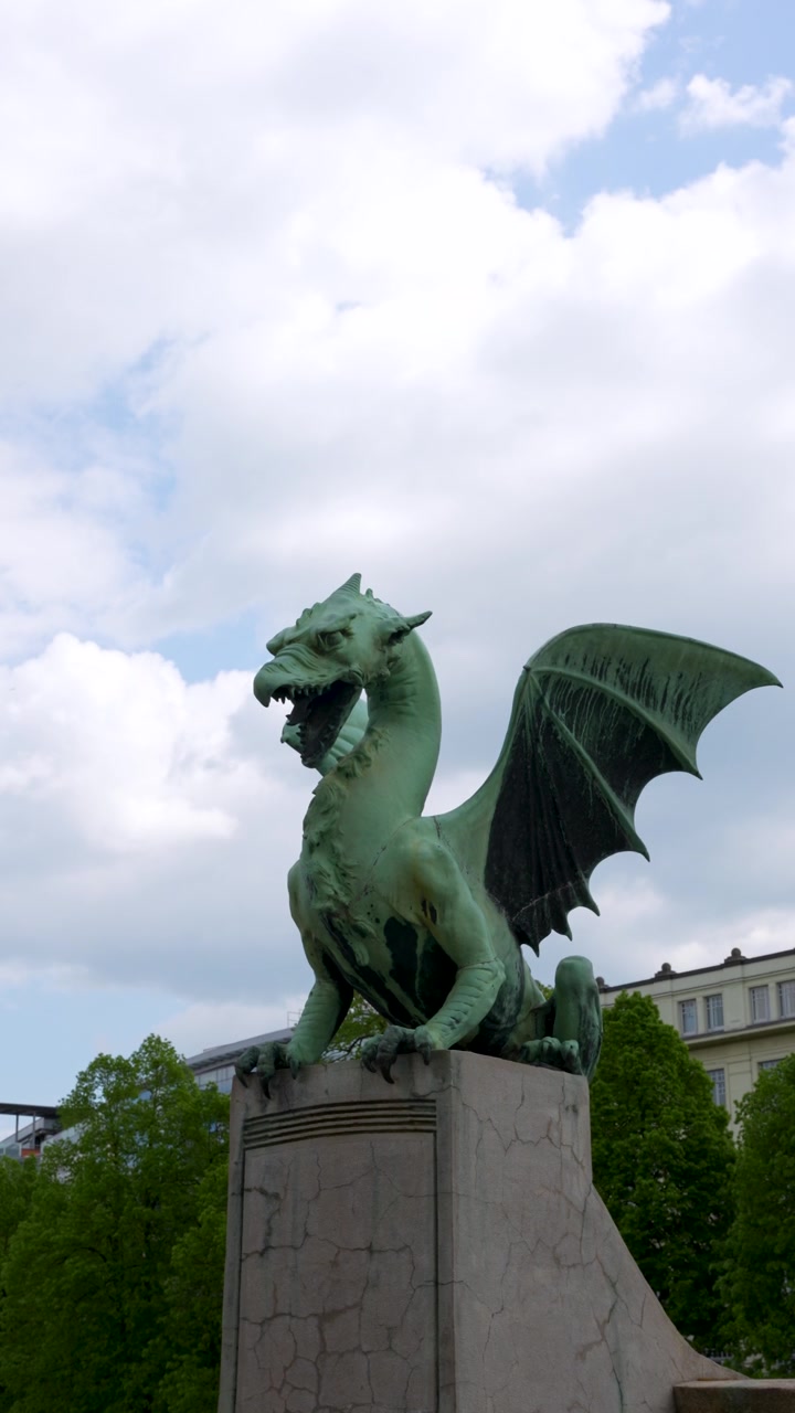 Uno scatto verticale dell'iconica statua del drago verde sul ponte Zmajski Most a Lubiana, Slovenia, sotto un cielo nuvoloso.