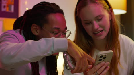 a young couple looking at a phone and laughing