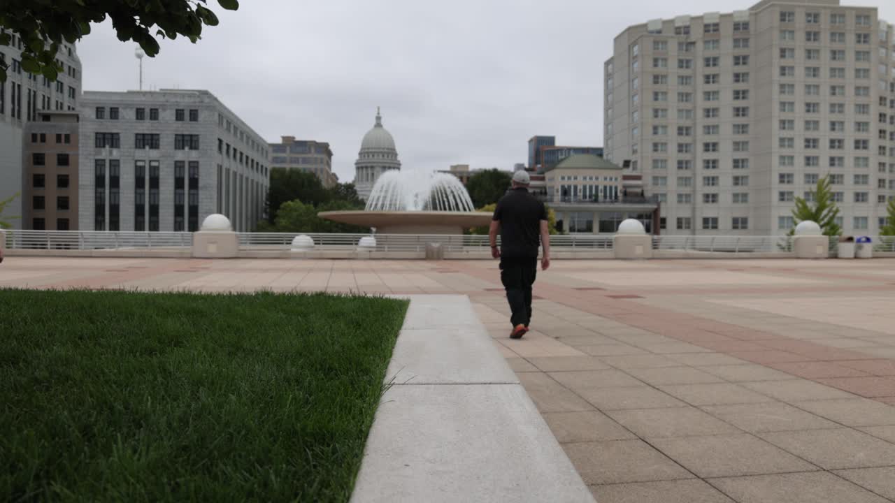 Uomo caucasico che cammina con cappello e abiti neri sulla Terrazza Monona a Madison, Wisconsin