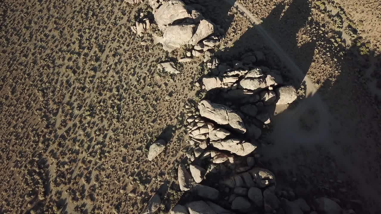 vista aérea de arriba hacia abajo sobre el desierto y las formaciones rocosas bajo la cordillera de las colinas de alabama, california