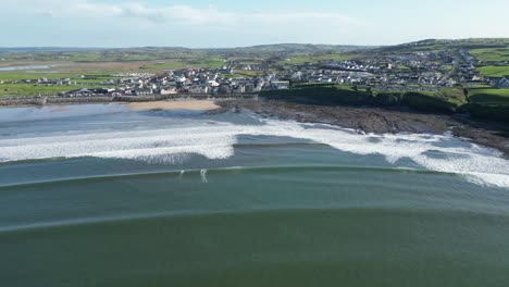 Toma-Aérea-En-órbita-De-Surfistas-Que-Caen-Olas-En-La-Playa-De-Lahinch-En-Un-Día-De-Verano