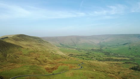 Drone-shot-from-the-top-of-Mam-Tor-looking-over-Winnats-Pass,-Peak-District-moving-towards-the-road-showing-moving-cars-and-mountains