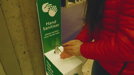 4k, slow motion shot of young woman using hand sanitizer before entering the underground station in london