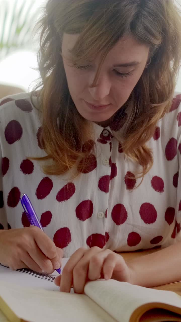 Young woman writes notes while studying at a cozy table