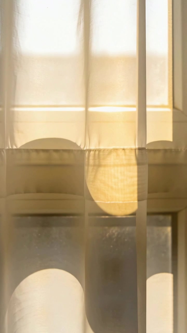 Vertical video: Gliding sheer curtain showing arch shadows on mullions as sunlight shifting at home
