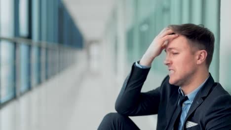 close-up of a young man in a business suit sitting on the floor in despair