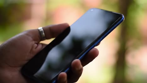 an intimate focus on a smartphone held in hand against a blurred natural background, highlighting modern technology in daily life