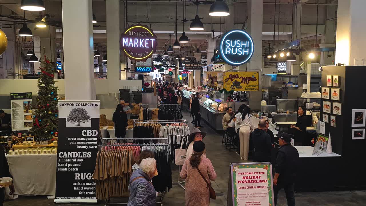 Bustling indoor market with food and retail stalls, featuring holiday decorations and many people