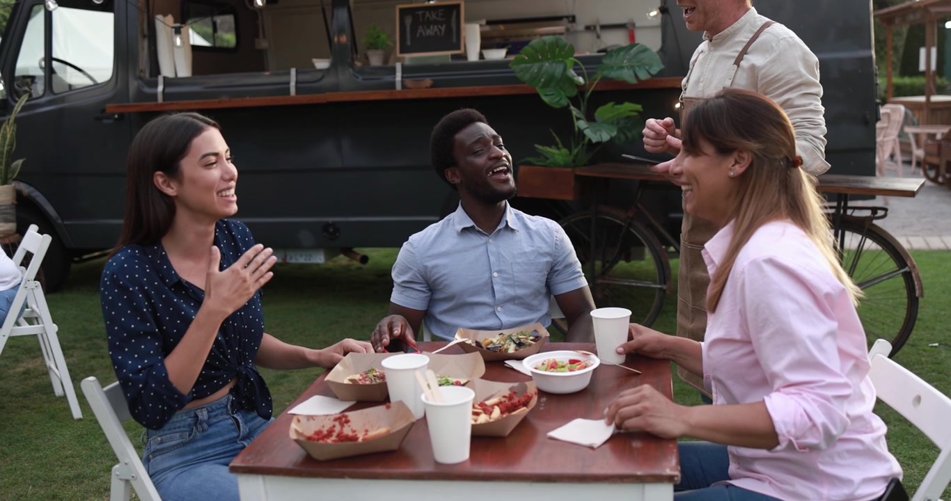 Multi-ethnic friends enjoying food and conversation at an outdoor food truck