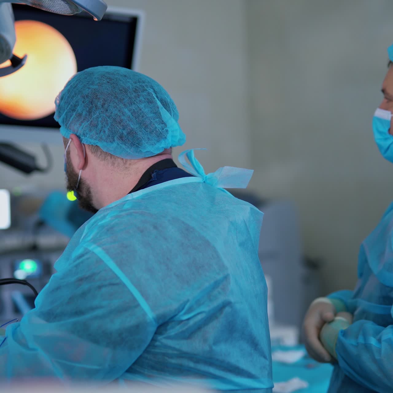 Surgery in hospital. Specialists doing medical procedure with modern technology equipment in hospital. Back view of doctors looking on monitor during operation.