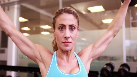 mujer súper en forma levantando pesas en crossfit