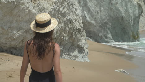 woman in a hat walks on the beach