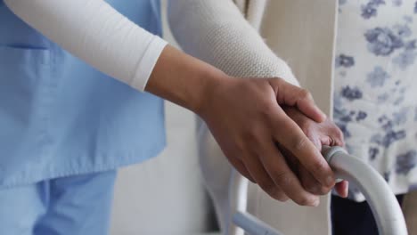 primer plano de una mujer médica africana estadounidense y un paciente mayor tomados de la mano