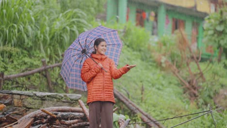 Young Indian village child walking on wet path with umbrella, enjoying soft rain in serene environment, 4k video