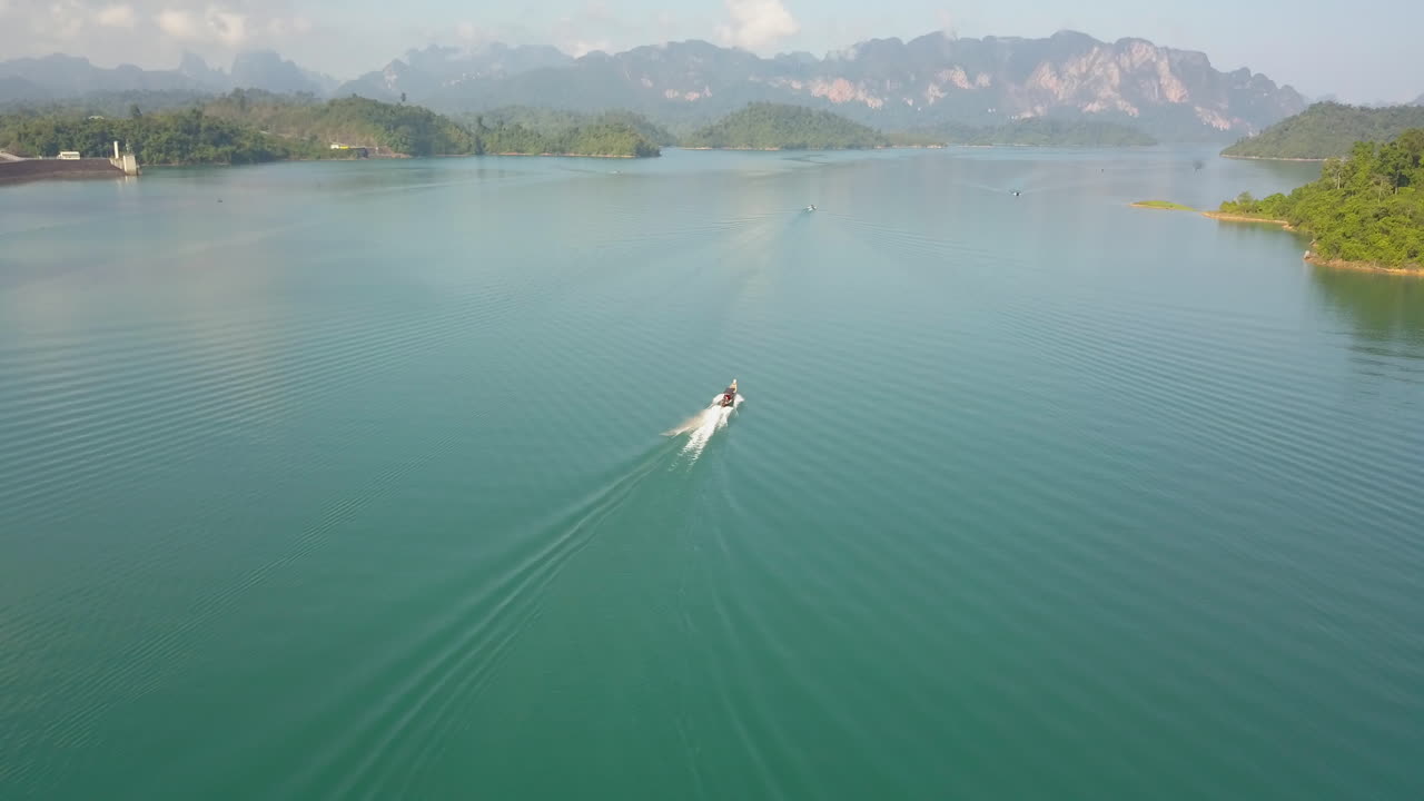 Motorboat Sailing in Colorful Lagoon Of Exotic Island, Tilt Up Aerial. Turquoise Water and Green Coast of Krabi Island, Thailand