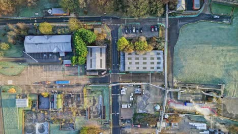 Overhead-aerial-footage-of-a-large-industrial-plant-showing-pipework-structures,-buildings,-cooling-towers,-steam,-and-work-vehicles