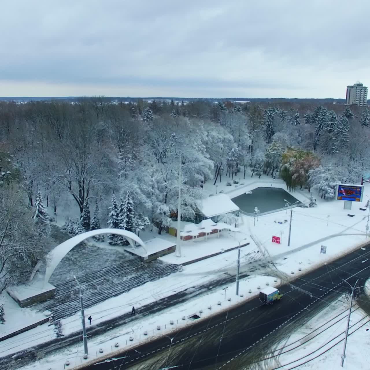 Transport road in the city near the big park. Snowy urban panorama in winter season. Aerial view