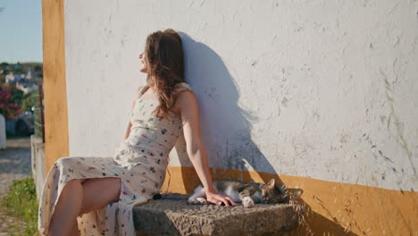 cute girl playing cat sitting rural bench. smiling woman enjoying summer sun