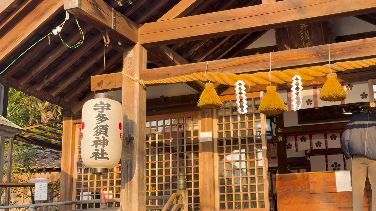 Static medium shot of a wooden Japanese temple entrance with lanterns and sacred rope