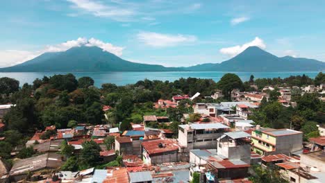 aerial village flyover toward lake and volcanoes - lake atitlan, panajachel, guatemala