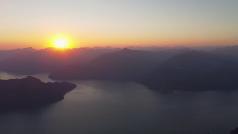 beautiful sunset over hazy mountain landscape with island and fjord - drone pan