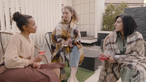 un agradable grupo multicultural de tres chicas hablando y bebiendo vino