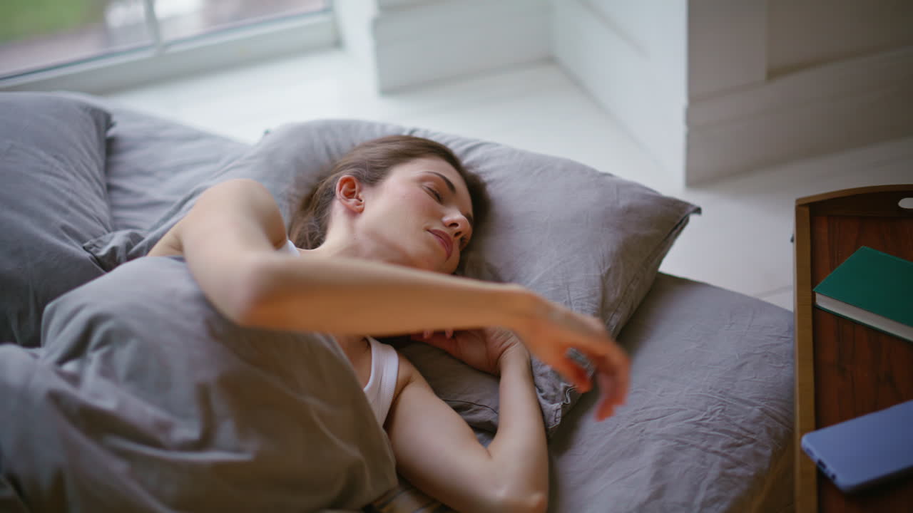 Closeup calm woman wakeup lying bed early morning. Brunette taking smartphone