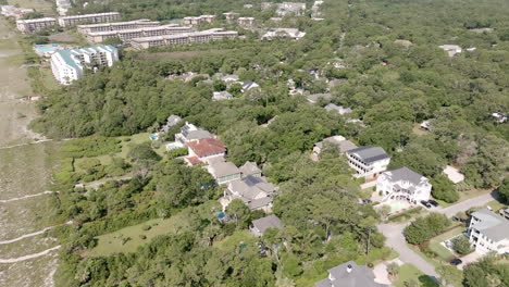 aerial view of beachside homes nestled in dense trees, separated from the shoreline by dunes and narrow walkways