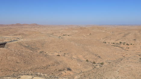 the vast and barren tunisian desert under a clear blue sky, aerial view