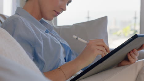 attractive young woman using digital tablet computer working at home browsing email messages with stylus pen enjoying mobile device technology