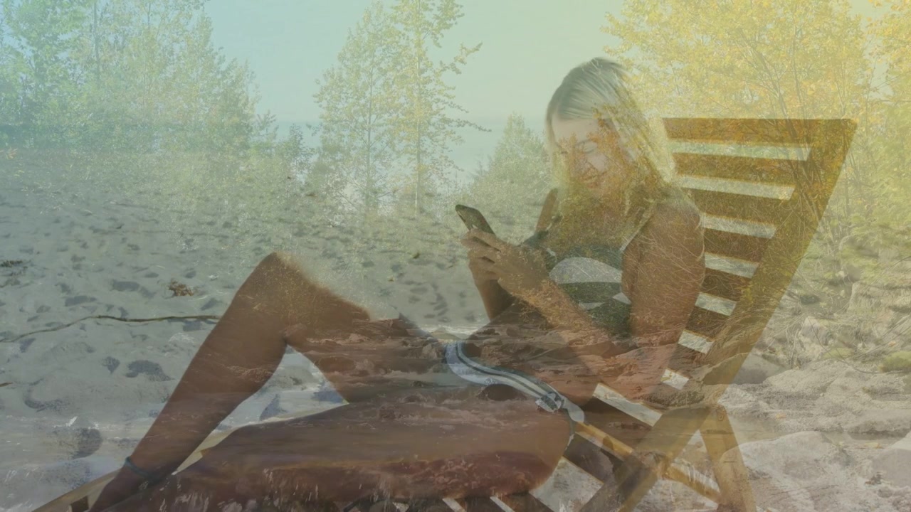 Woman reclining on beach glancing, tapping phone, scrolling, waves, trees over her for leisure