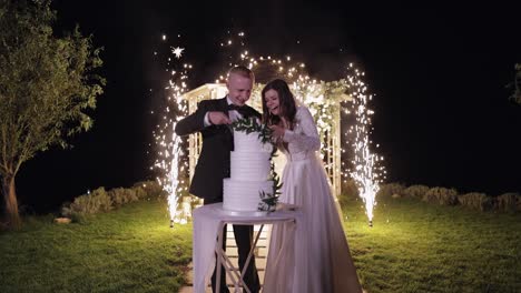 la novia y el novio cortando el pastel de boda con chispas