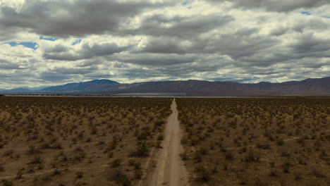 cloudscape aerial hyper lapse over the mojave desert with leading lines from a dirt road