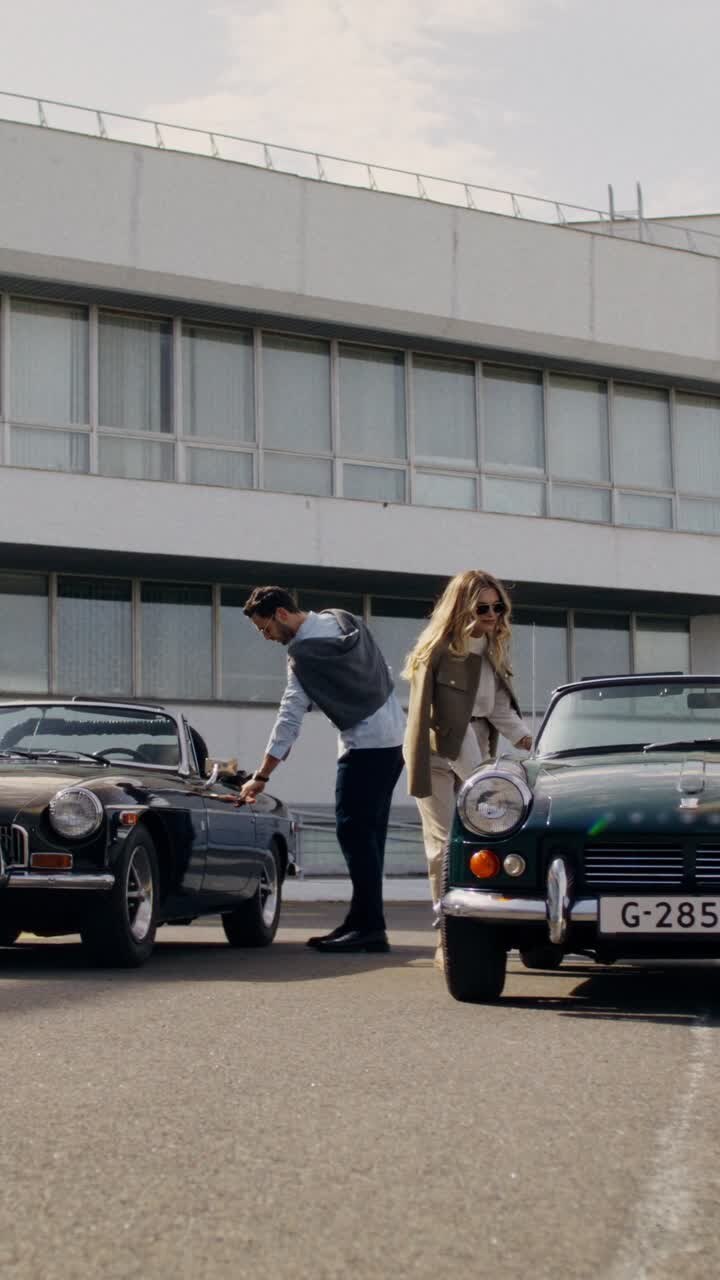 Pareja posando frente a coches clásicos