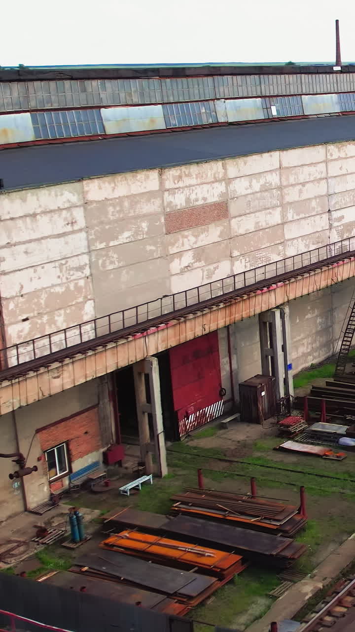 Aerial view of an industrial railroad facility with stacked materials and train cars