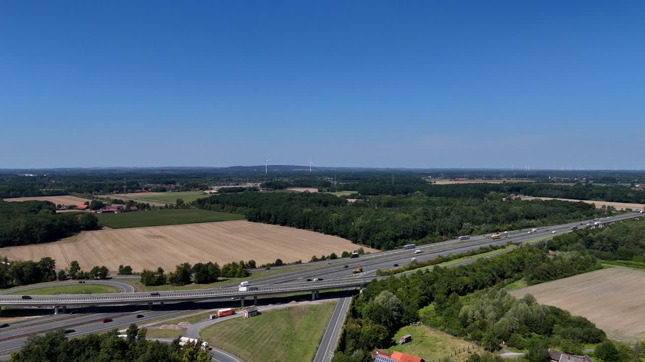 Aerial establishing of German expressway highway with traffic on sunny summer day. Historic countryside farm houses And road junction on autobahn. Wide shot. Blue sky and sunlight