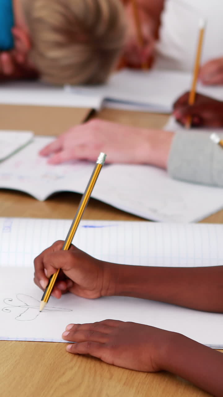 Vertical video of an African American boy and Caucasian boy drawing at school
