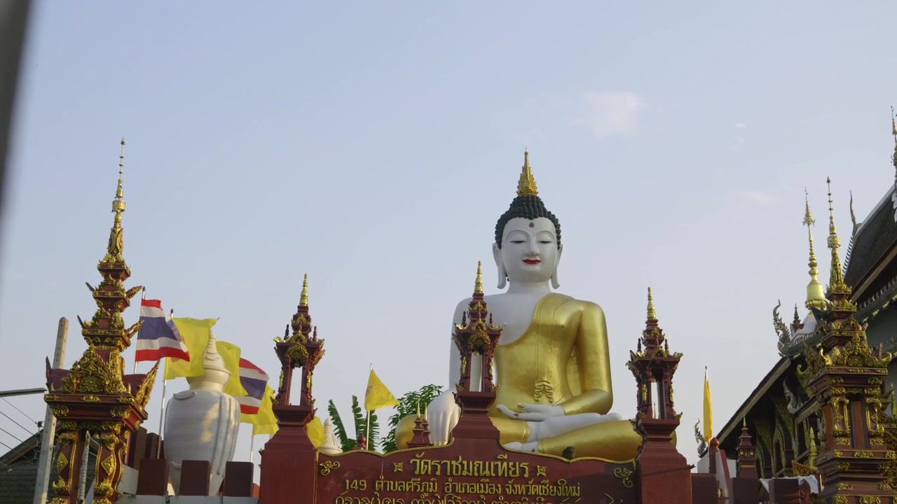 Inquadratura cinematografica a scorrimento che rivela una statua di Buddha in un tempio thailandese.